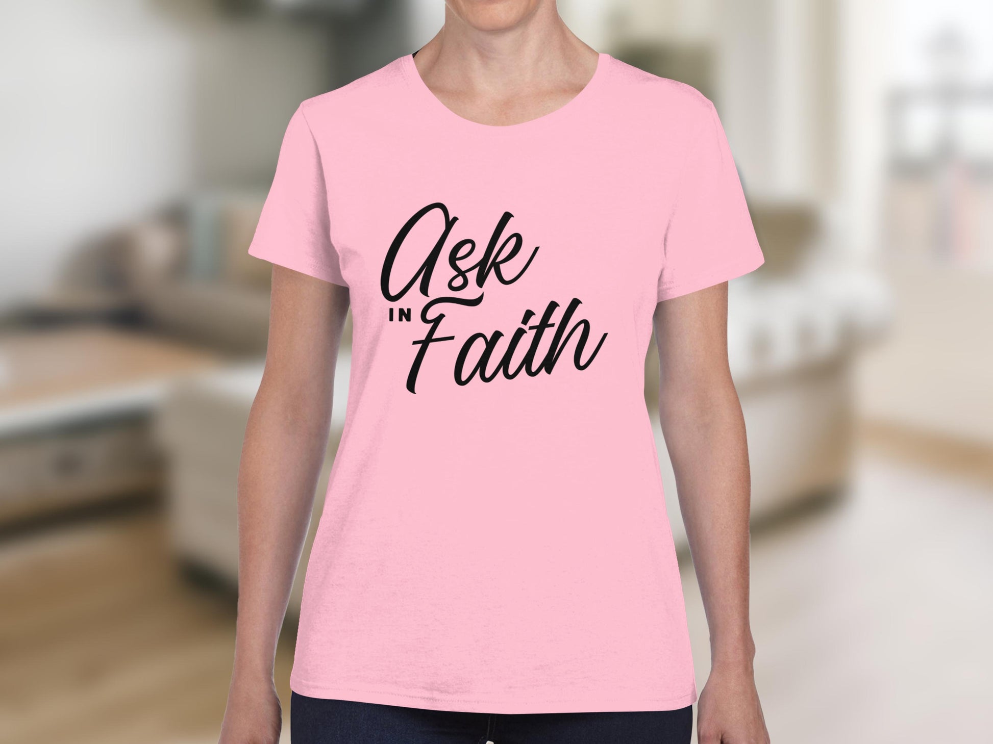 Pink t-shirt with "Ask in Faith" text on a blurred background.